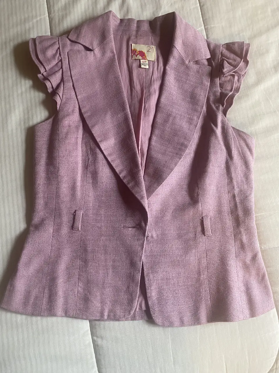 Chaleco sin mangas de color rosa con detalles de volantes en los hombros. Ideal para un look elegante y sofisticado.