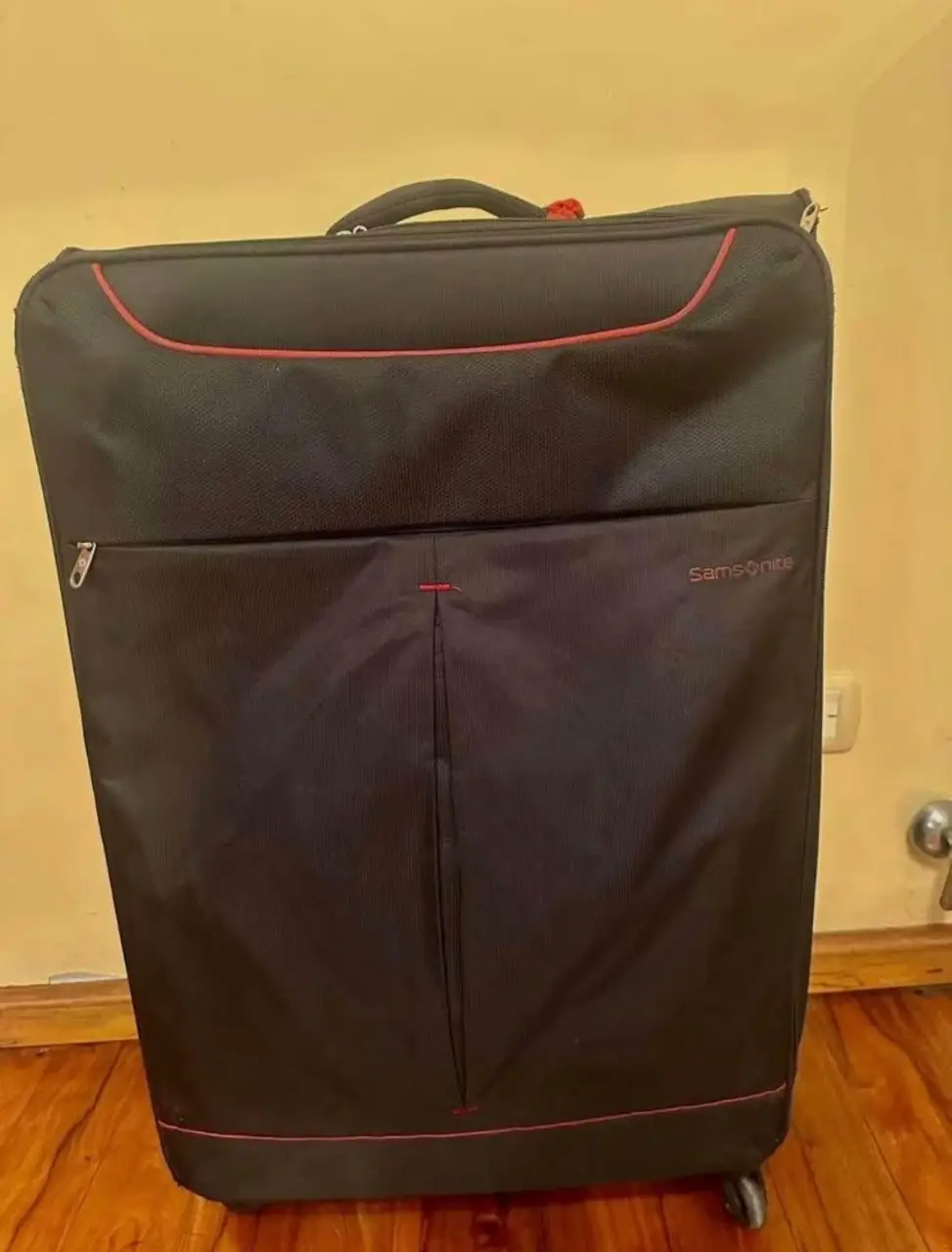 Valija Samsonite negra, ideal para viajes. Amplia y resistente, con detalles en rojo. Perfecta para llevar todo lo necesario.