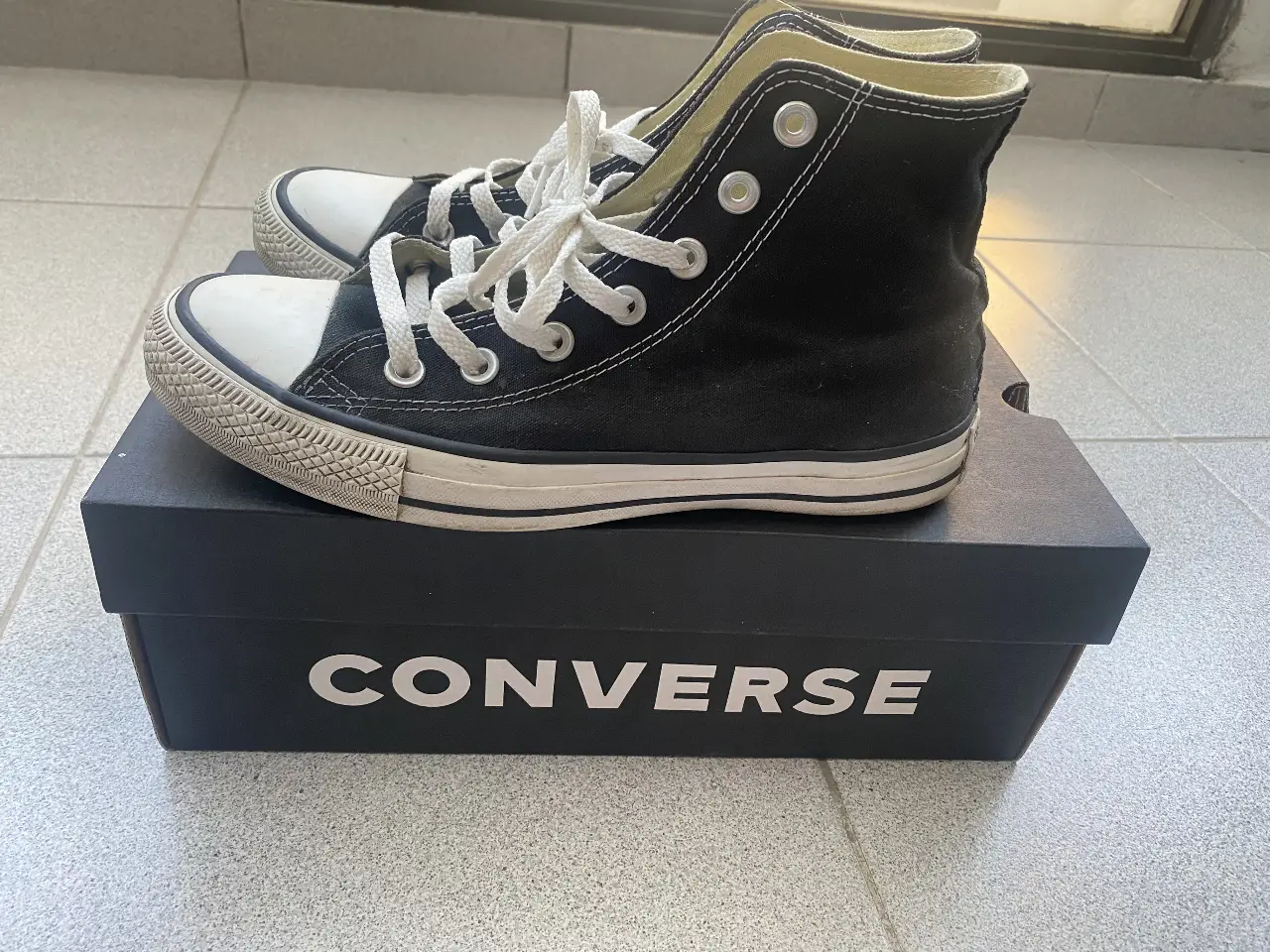 Zapatillas Converse All Star negras de caña alta, con puntera blanca y suela de goma. Clásico diseño urbano, ideales para un look casual y versátil. Unisex