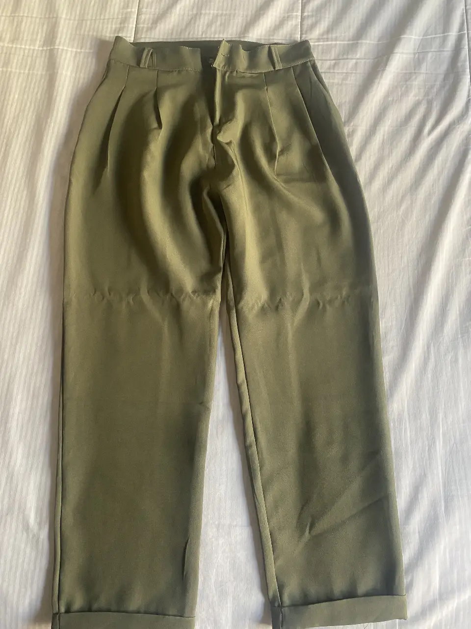 Pantalón sastrero verde militar, tiro alto, con pinzas y dobladillo en el bajo. Ideal para un look elegante y moderno.