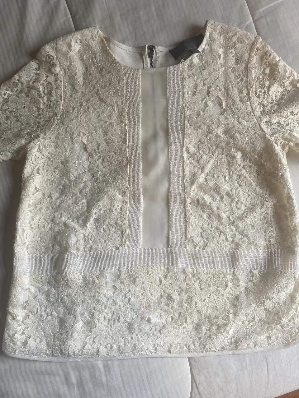 Blusa de encaje color blanco con cierre en la espalda. Ideal para un look elegante y femenino.