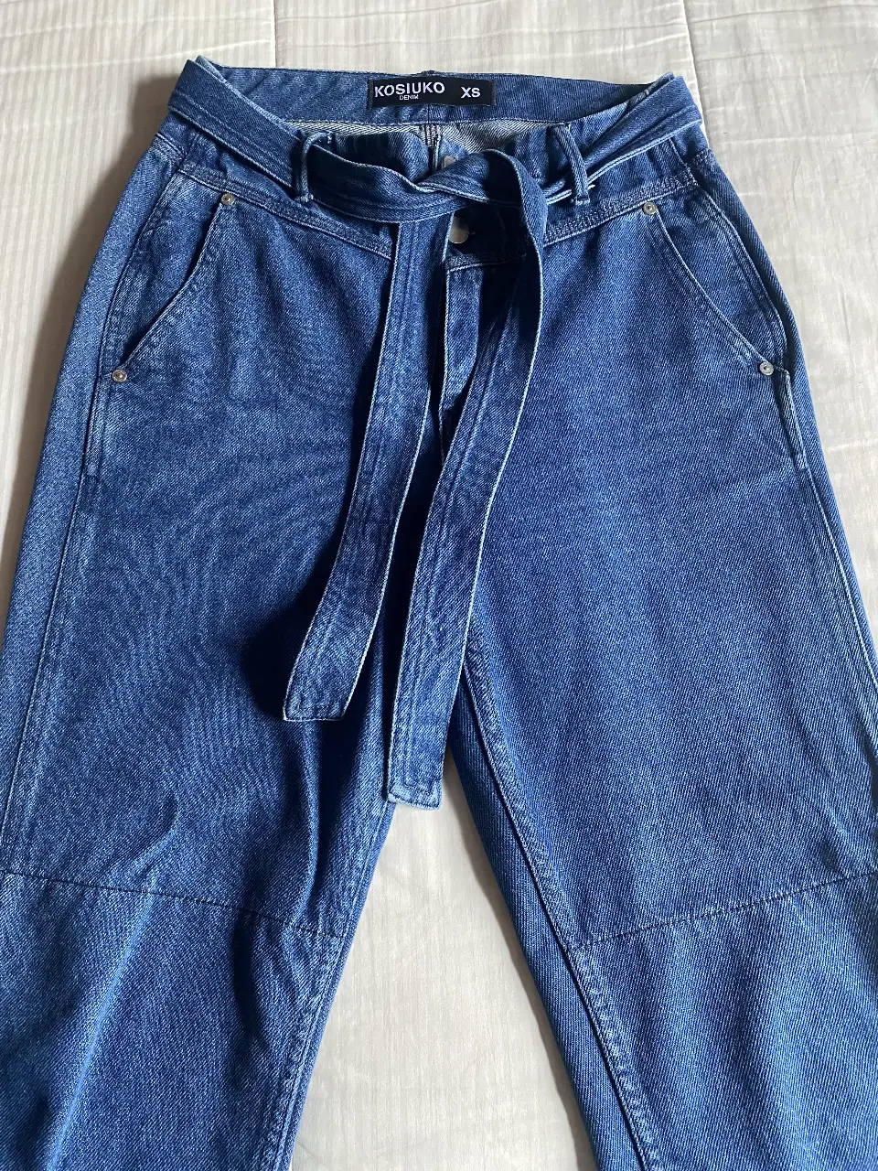 Pantalón de jean azul con cinturón, tiro alto y corte suelto. Ideal para un look casual y moderno, Talle XS