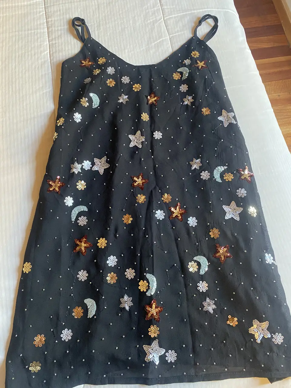 Vestido mini negro con detalles de lentejuelas doradas y plateadas en forma de estrellas, flores y lunas. Con forro x dentro y breteles finitos, ideal para fiestas y cualquier eventos.