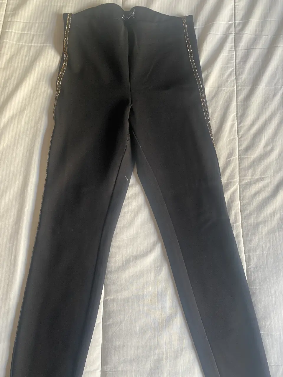 Pantalón negro de vestir con detalle dorado en los laterales. Ideal para un look elegante y sofisticado.