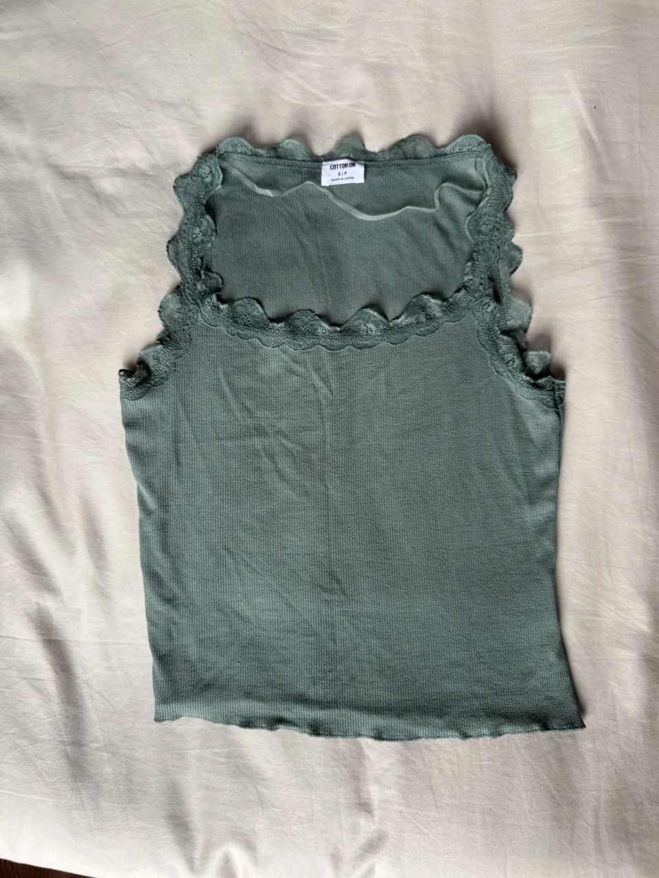 Musculosa de algodón color verde musgo con detalles de encaje en el escote y en el ruedo. Escote cuadrado.