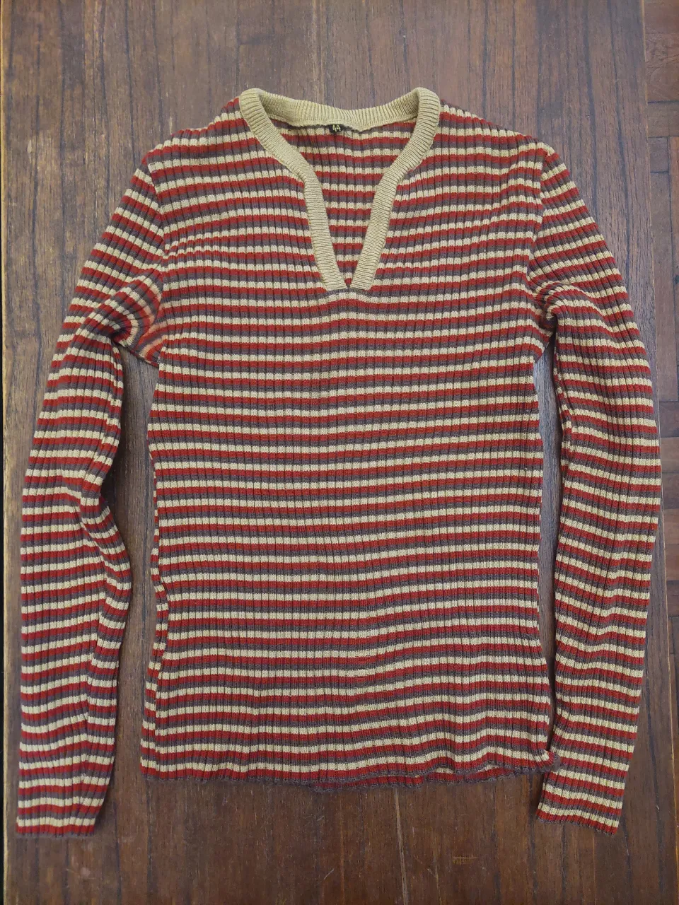 Sweater de rayas finas en tonos rojos, beige y marrones. Cuello en V con detalle de tejido.