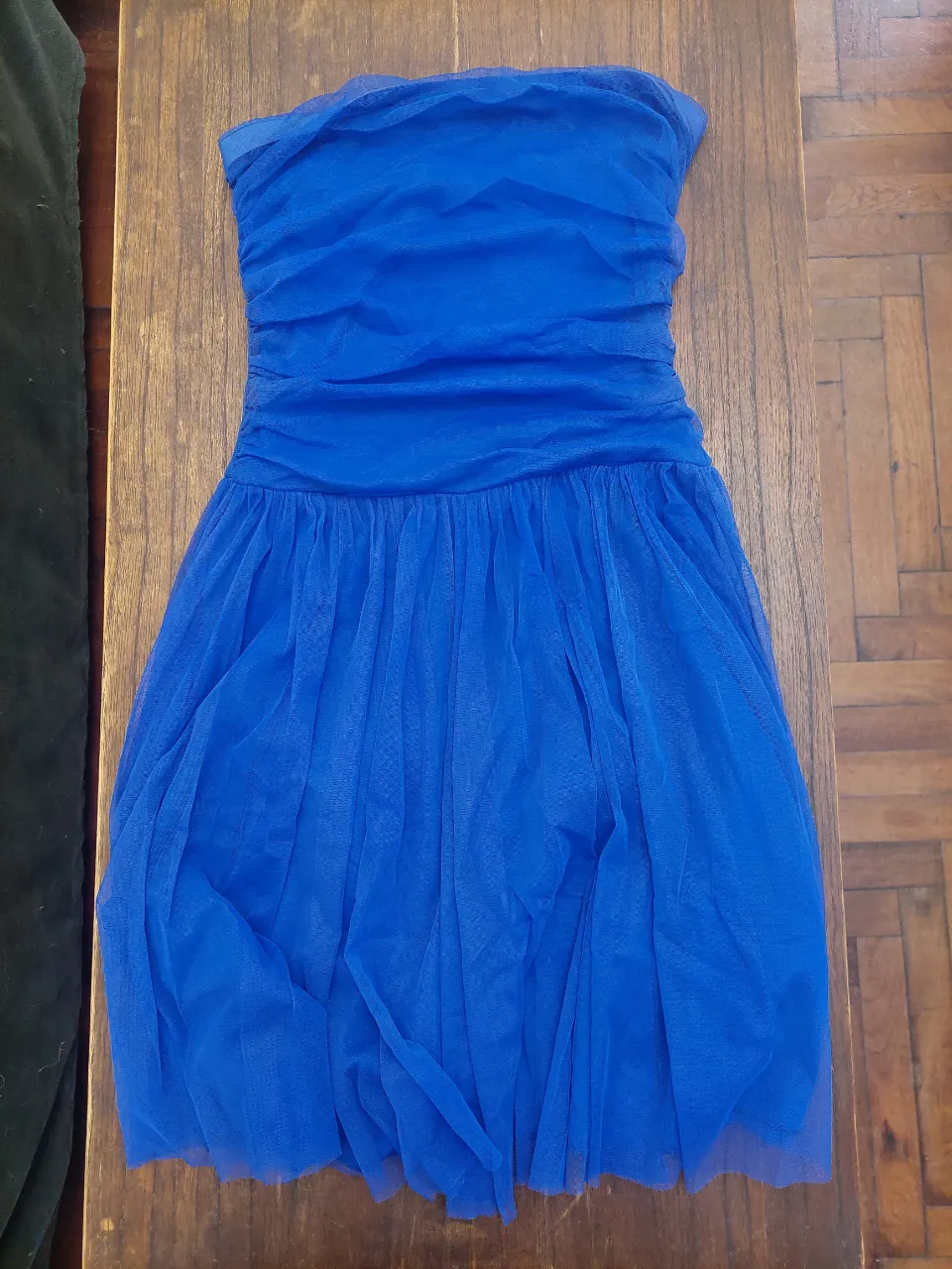 Vestido strapless azul eléctrico, con detalles fruncidos en la cintura y falda de tul. Ideal para fiestas o eventos especiales.