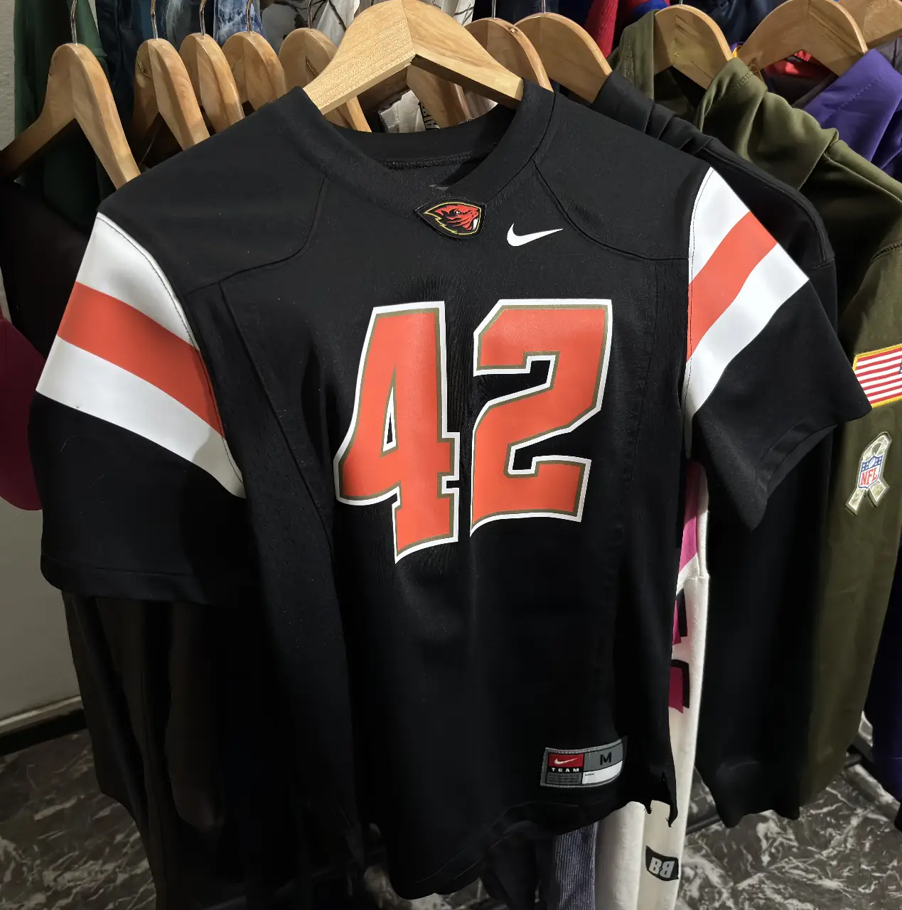Camiseta de fútbol americano de la Universidad de Oregon State, color negro con detalles en naranja y blanco. Número 42 en el frente y mangas con detalles a rayas. Marca Nike.