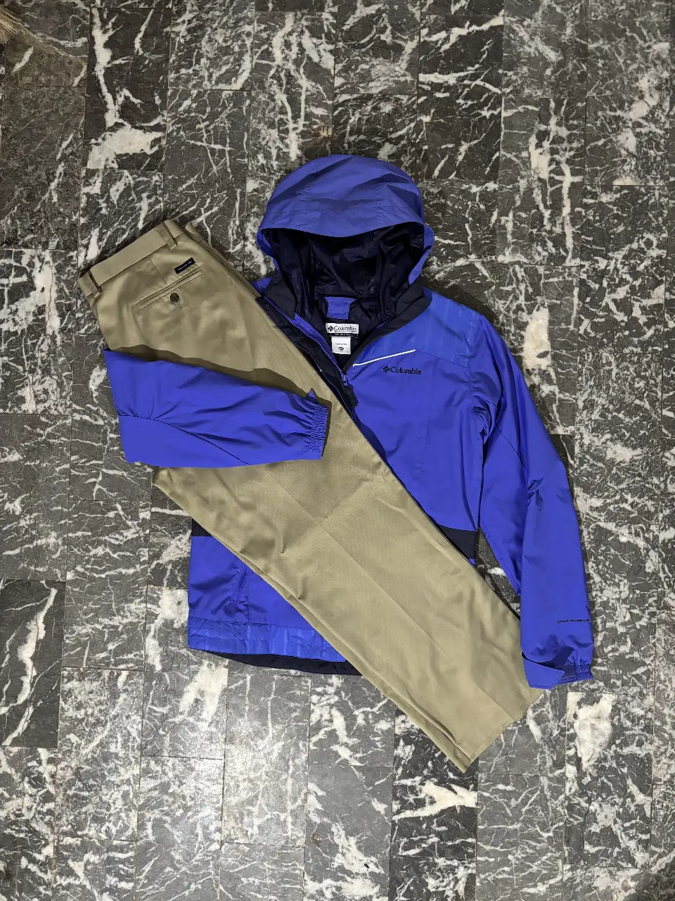 Conjunto para mujer, compuesto por campera rompevientos impermeable azul Columbia con detalles en negro y pantalón chino color khaki. Ideal para actividades al aire libre o un look casual.