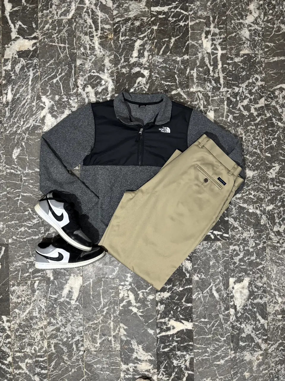 Buzo con cierre The North Face, combinado en gris y negro. Ideal para un look casual y abrigado.