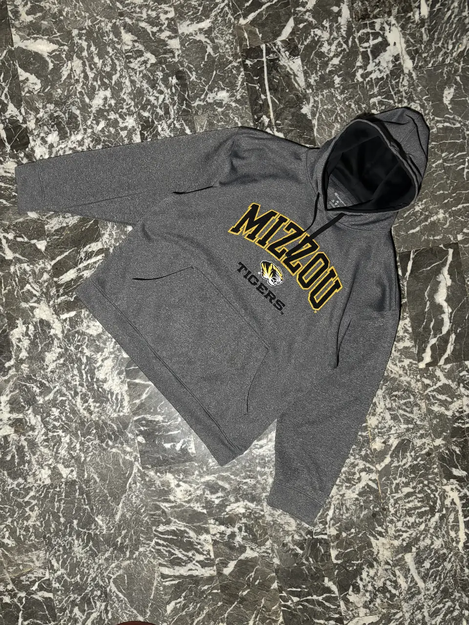 Buzo canguro gris de hombre con estampado "Mizzou Tigers" en amarillo y negro. Ideal para un look casual y deportivo.