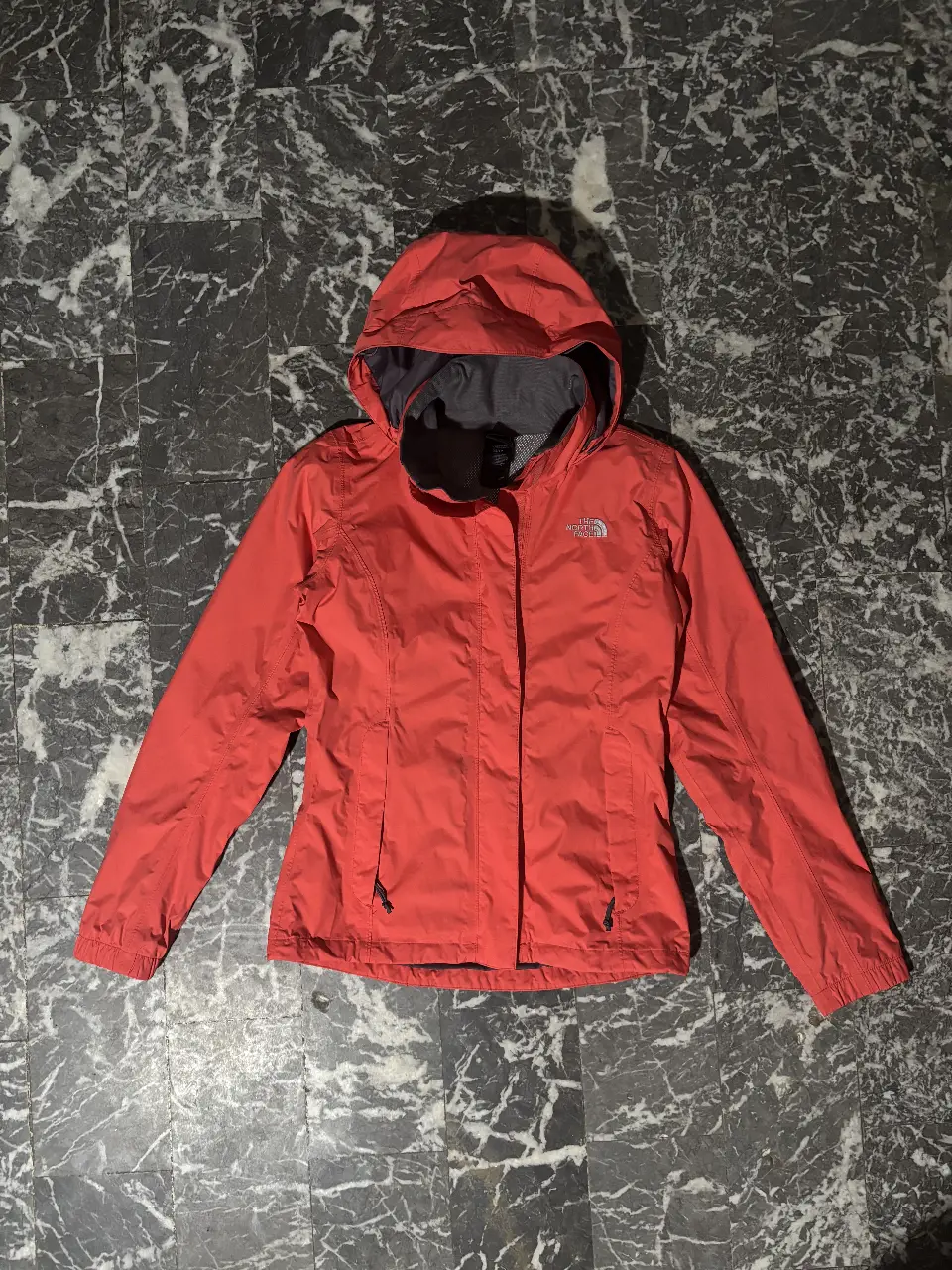 Campera rompevientos impermeable The North Face salmon para mujer, con capucha y cierre. Ideal para actividades al aire libre y protegerse de la lluvia.