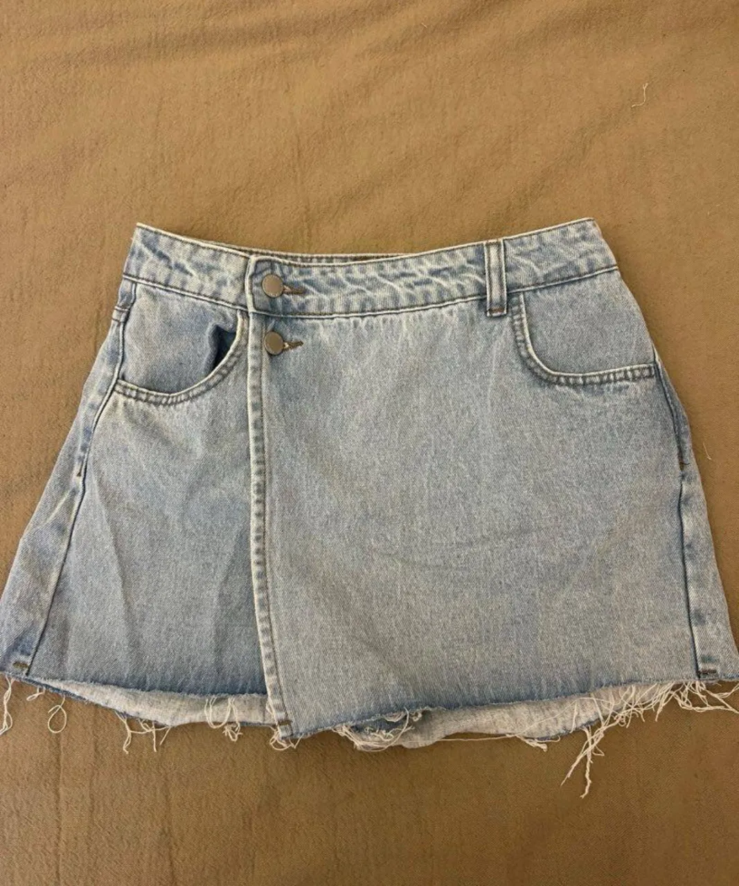 Short de jean de mujer, con diseño asimétrico y detalles deshilachados. Talle 27, ideal para un look casual y moderno.