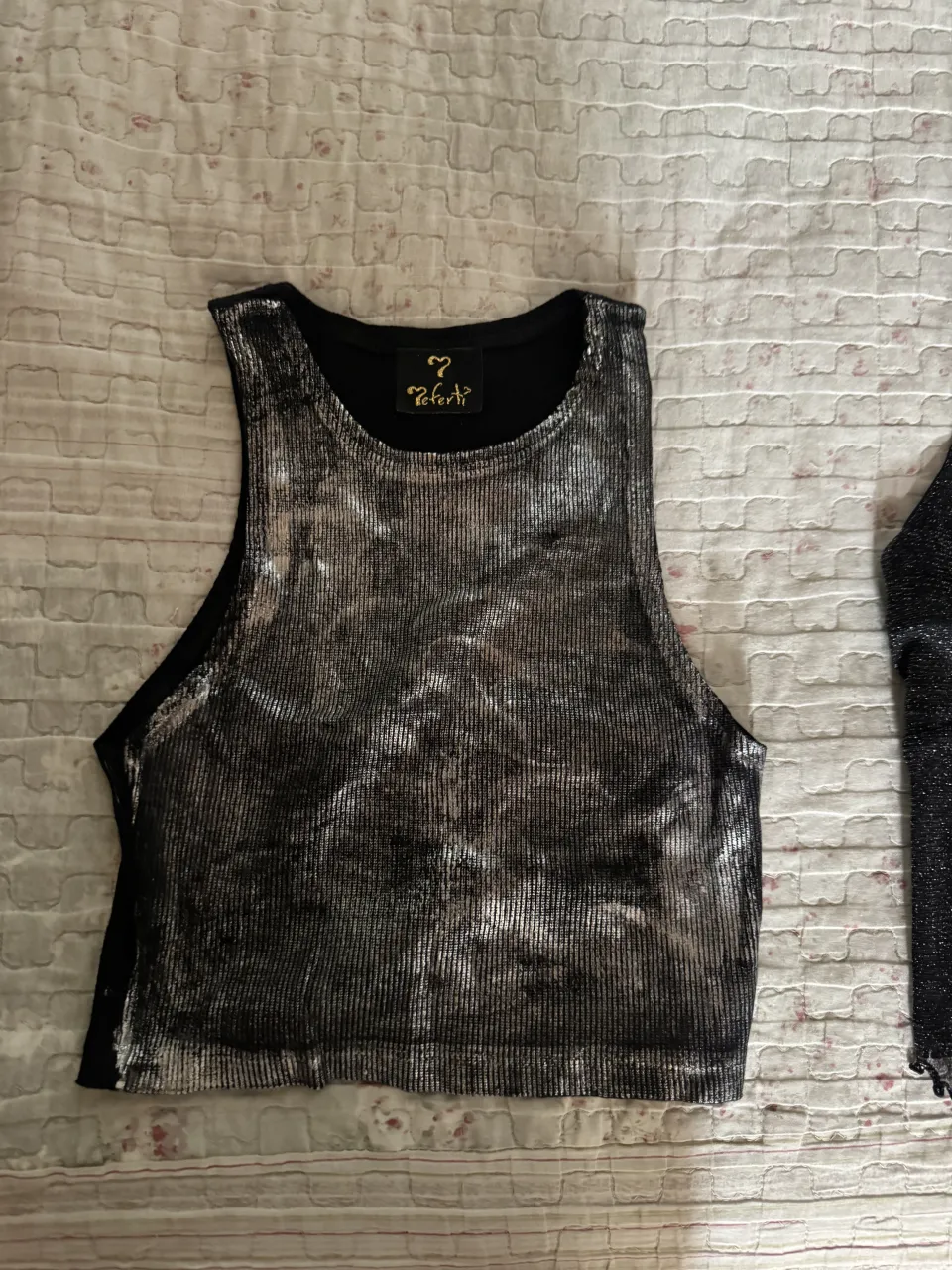 Musculosa plateada con detalles en negro. Posee un estampado metálico y textura acanalada.