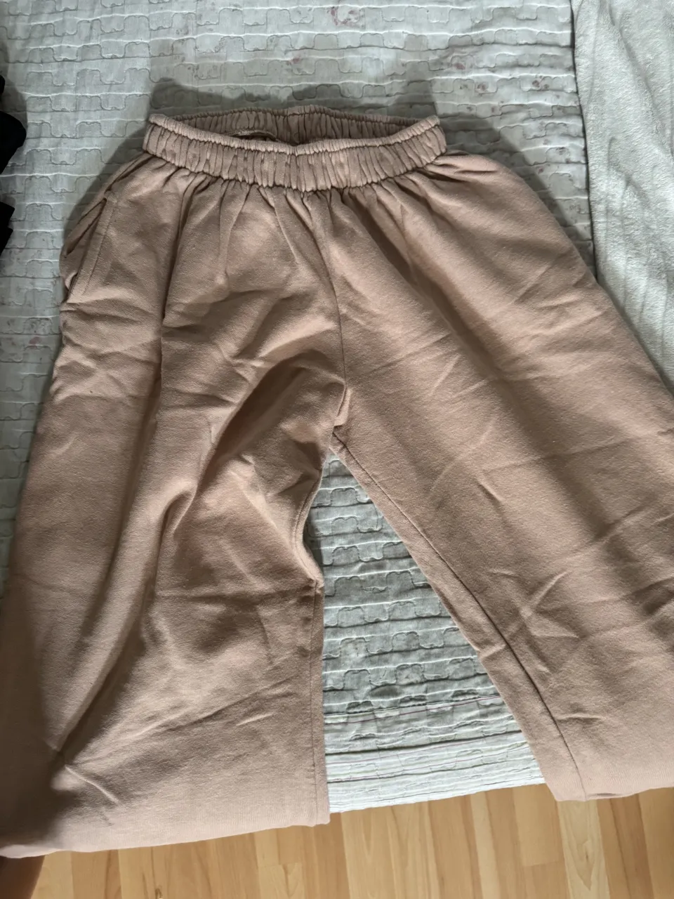 Pantalón de tela color beige con cintura elastizada y bolsillos laterales.