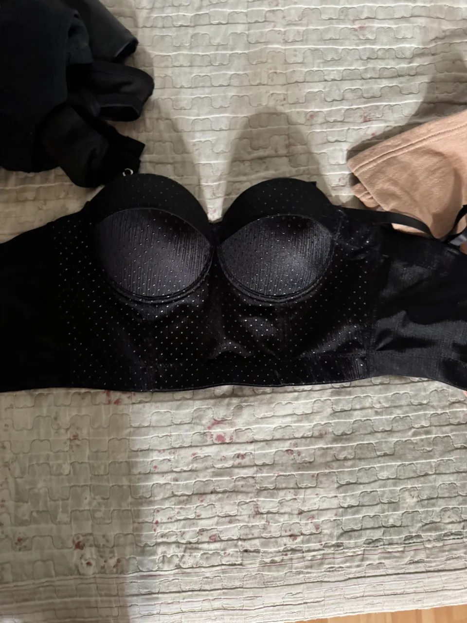 Corpiño negro con detalles de pequeños puntos plateados y franjas verticales en las copas. Posee un diseño strapless.