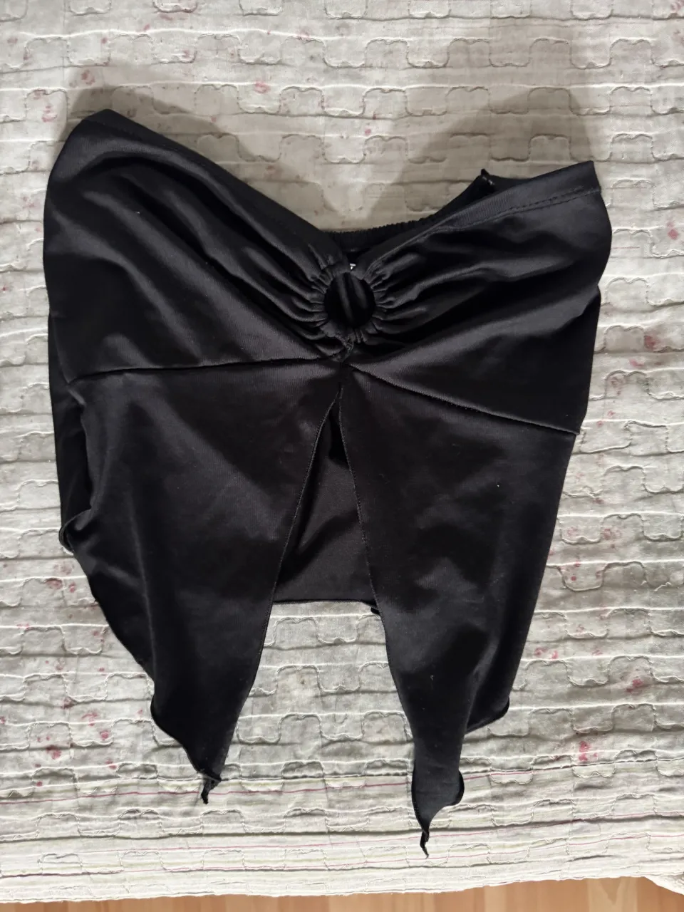 Top negro con detalle de aro metálico en el escote y tajos en la parte inferior.