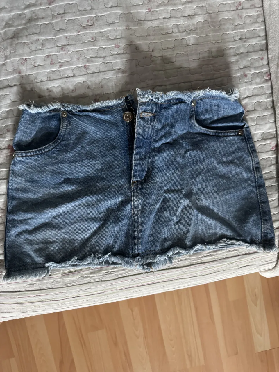 Pollera de jean corta con roturas y detalles deshilachados en los bordes.