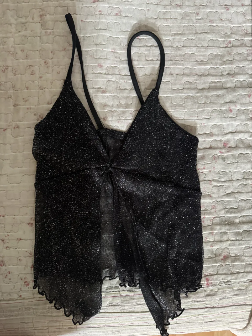 Top negro con brillos y tiras finas. Posee volados en el borde inferior.