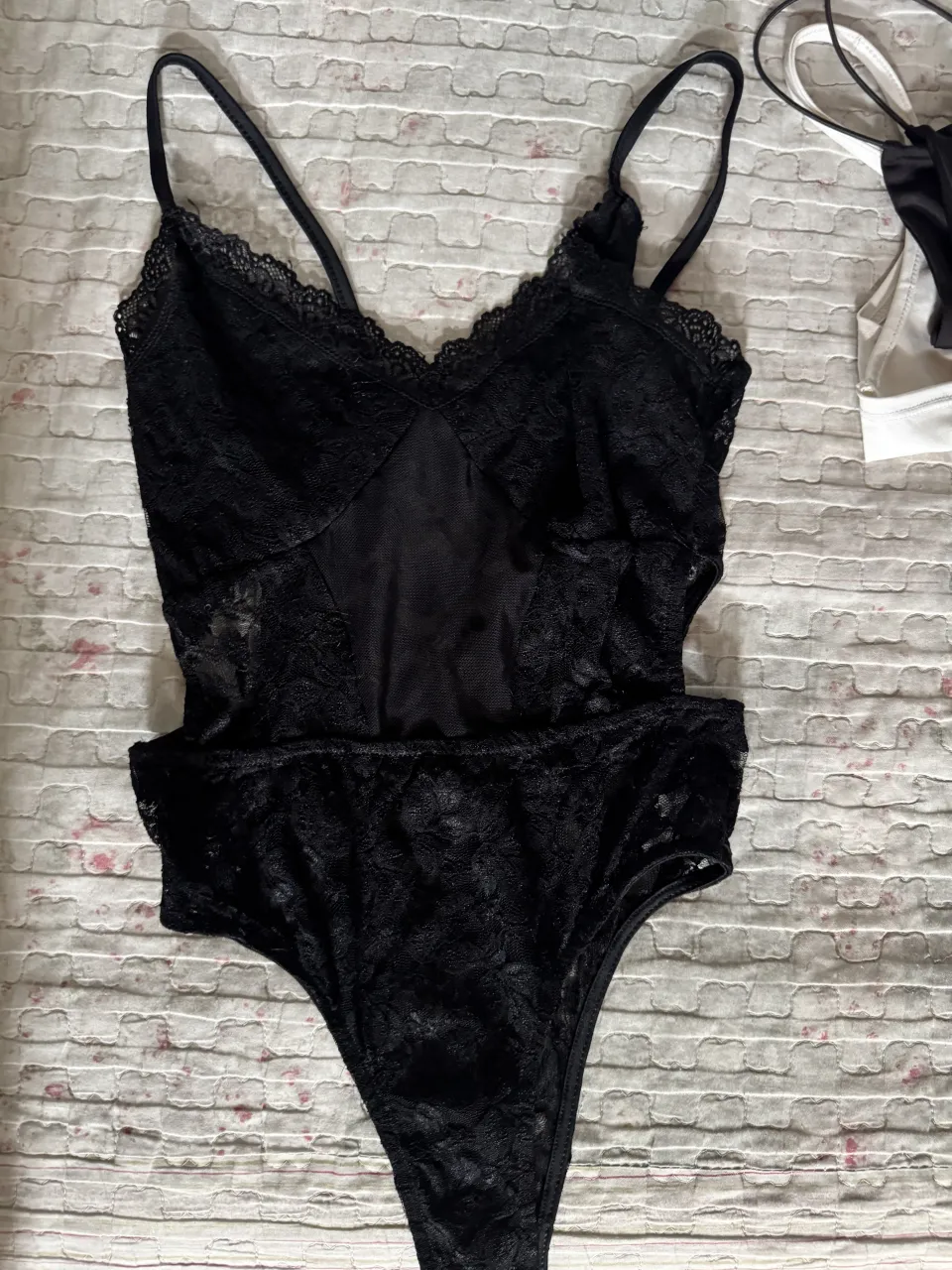 Body de encaje negro con tiras finas y detalles de puntilla en el escote. Posee un corte tipo culotte en la parte inferior.