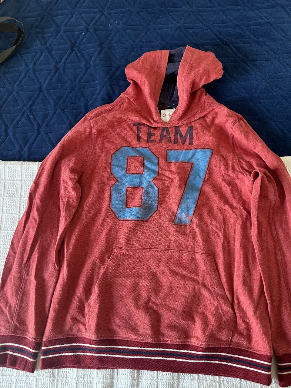 Buzo canguro rojo con estampado "TEAM 87" en azul. Talle XL (16) de la marca Cat & Jack. Ideal para un look deportivo y casual. 