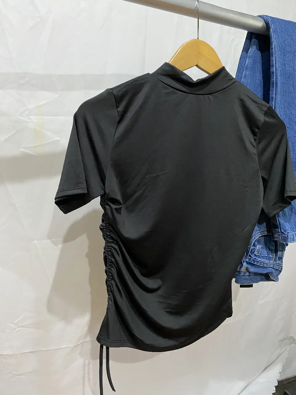 Remera negra de cuello alto con detalle fruncido en un lateral. 