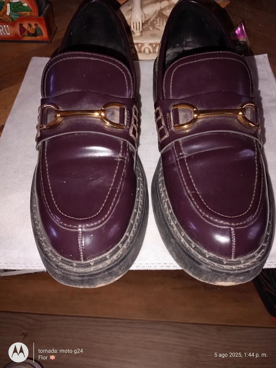 Mocasines de cuero color borgoña con detalle de hebilla dorada. Ideales para un look elegante y moderno.