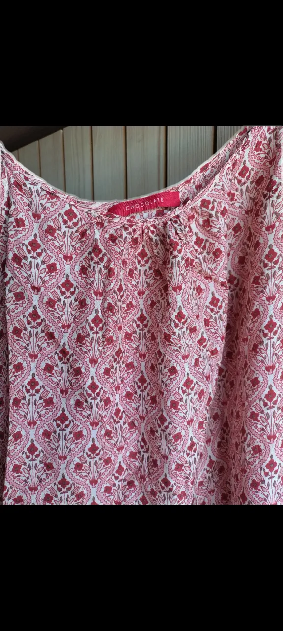 Musculosa estampada con flores rojas y detalles en blanco. Tiene tiras finas.