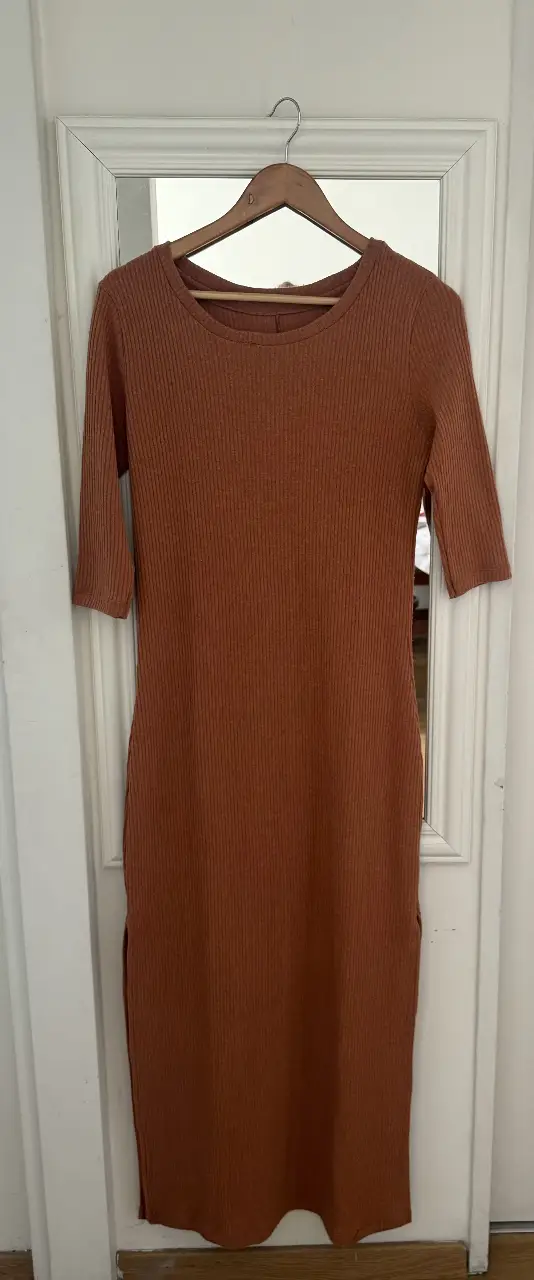 Vestido midi de tela tipo tejido de punto acanalado. El talle estaría entre un S - M. Color marrón tostado. Manga 3/4, cuello redondo y picos a los laterales. Ideal para estar arreglada con un look casual y cómodo. Casi sin uso! 