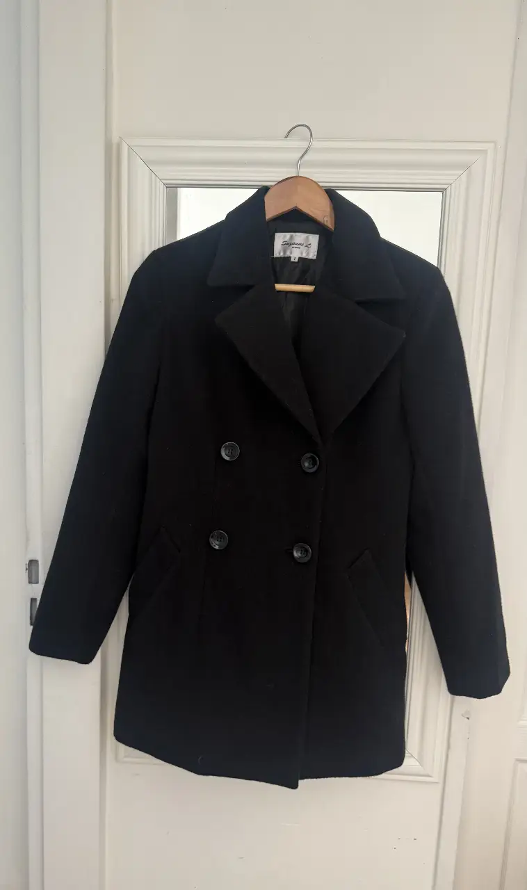Tapado negro de paño, con corte clásico y botones. Ideal para el invierno, este abrigo es un básico atemporal para cualquier guardarropa.