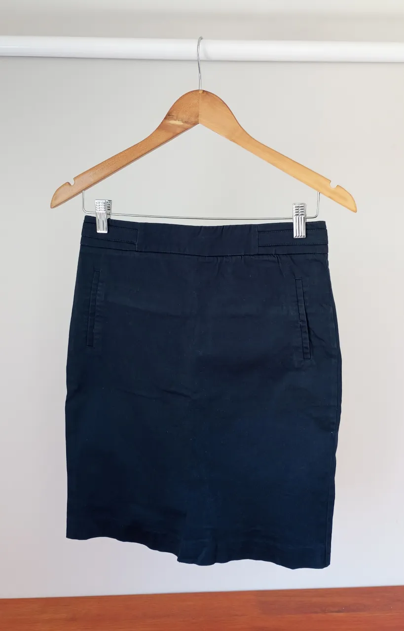 Pollera azul marino, con bolsillos delanteros y traseros. Cierre en la parte trasera.
se cortó e hizo ruedo a mano.