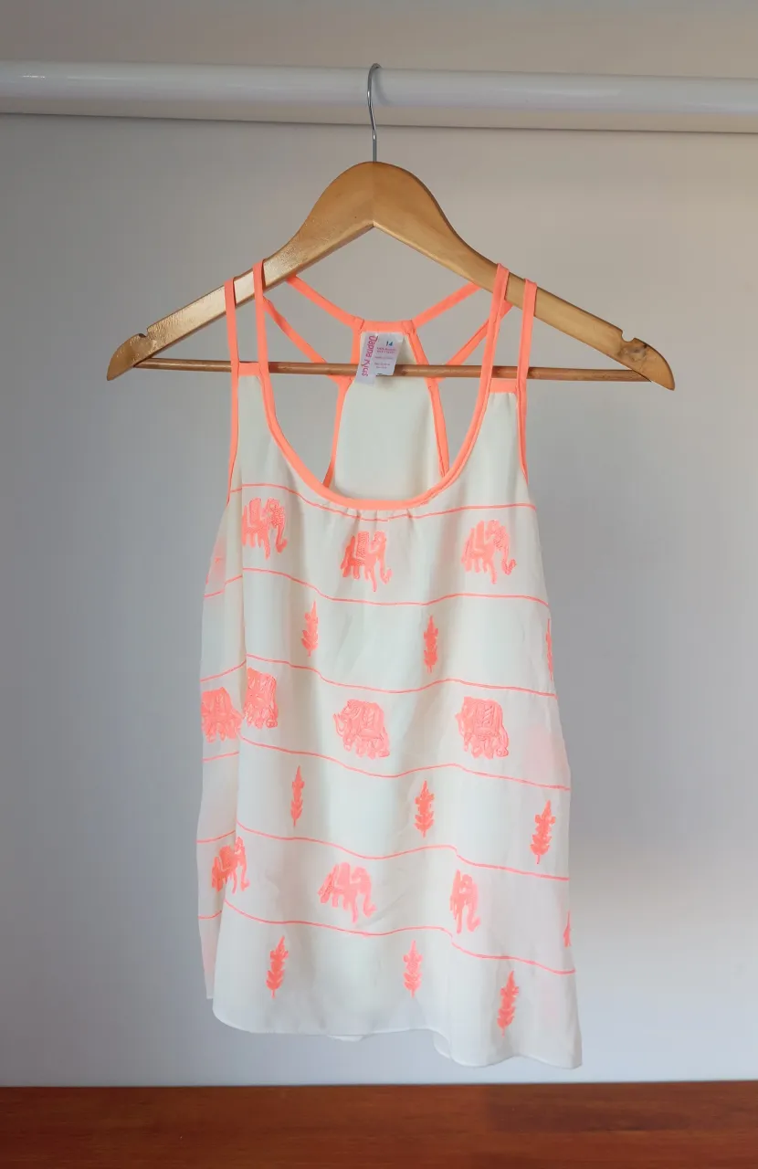 Musculosa blanca con estampa de elefantes y hojitas en color naranja neón. Ideal para el verano, súper fresca y canchera.