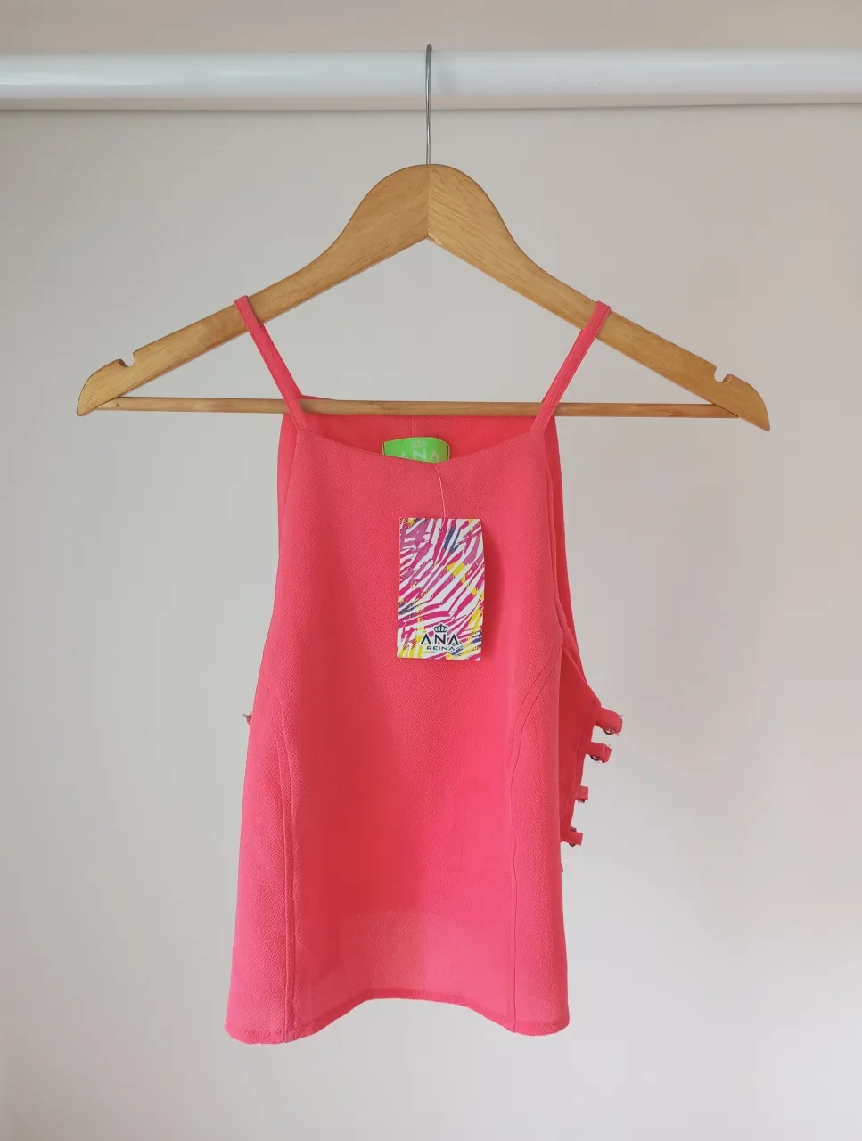 Top rosa con tiras finas y detalles de argollas y tiras en los laterales.