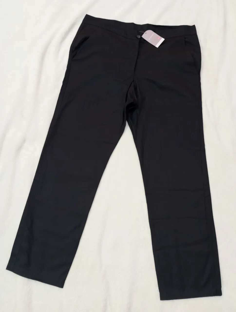 Pantalón negro liso con dos bolsillos delanteros y un botón en la cintura.