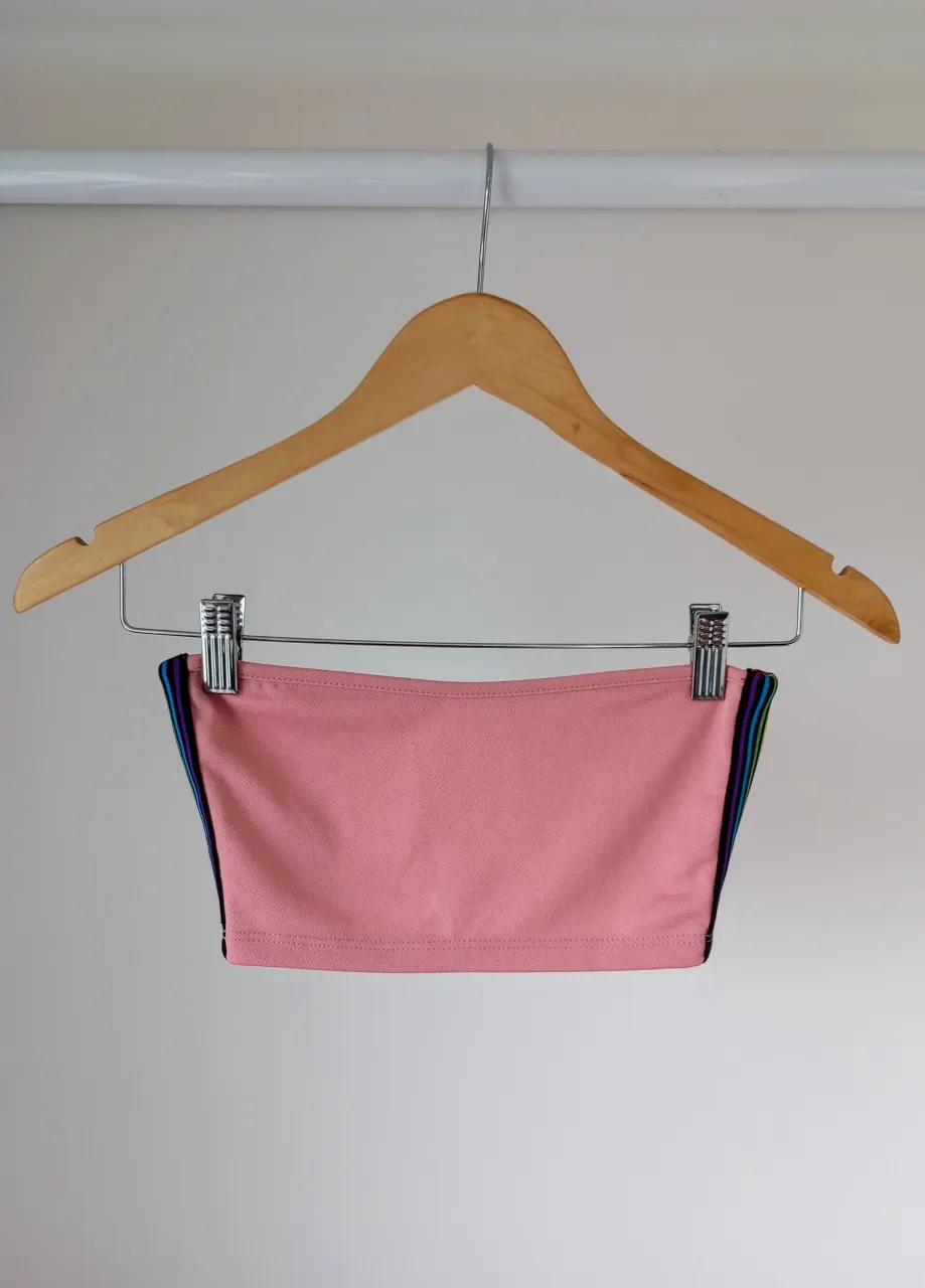 Top deportivo rosa strapless con detalles de tiras de colores en los laterales.