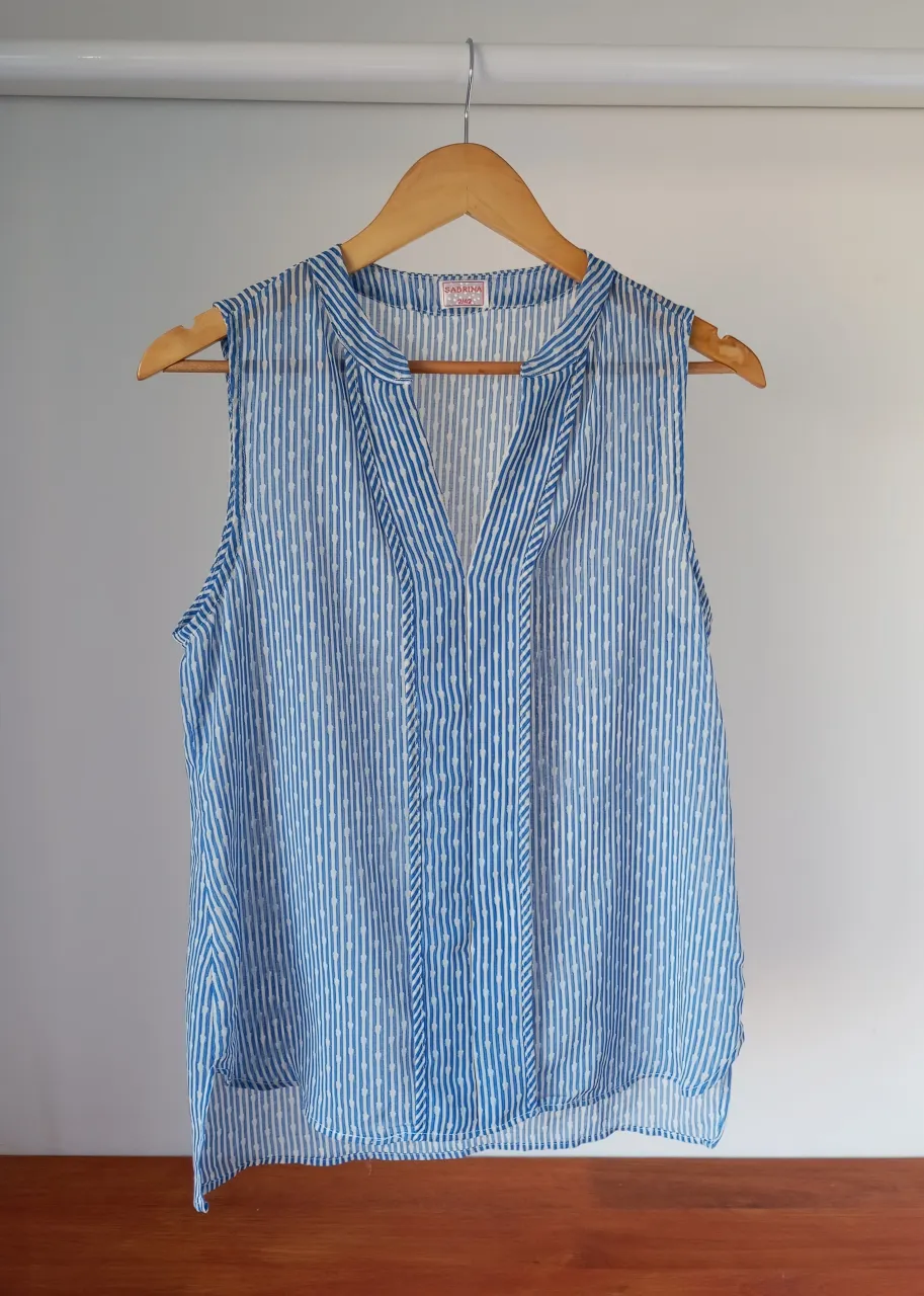 Musculosa de gasa estampada con rayas verticales azules y detalles blancos. Posee cuello en V con cordones para atar. Ideal para un look fresco y casual.