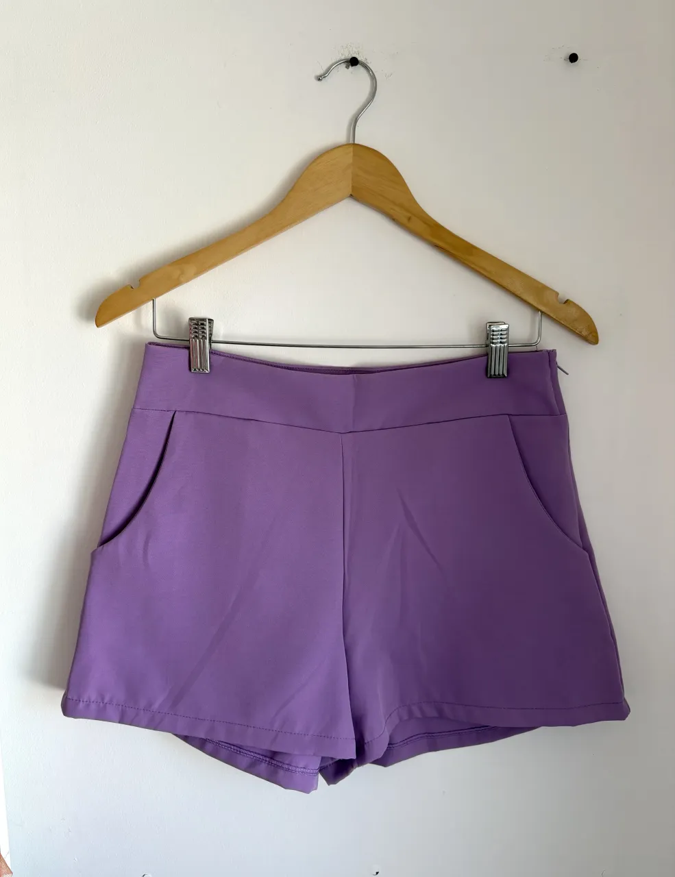 Shorts de vestir color lila con bolsillos delanteros y traseros simulados. La etiqueta dice talle L pero corresponde a un M.