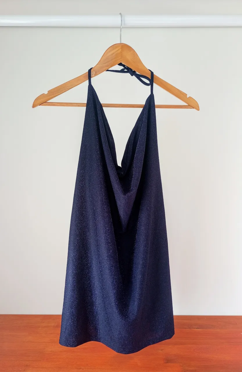 Vestido de lurex azul oscuro con brillos, cuello halter y espalda descubierta.