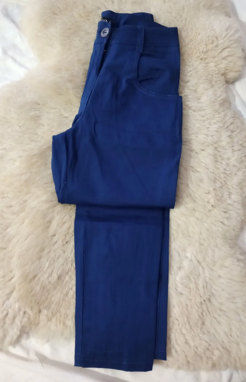 Pantalón elastizado azul de vestir, tiro alto, con bolsillos delanteros y traseros. Detalle de cierre en los tobillos. Ideal para un look elegante y moderno.