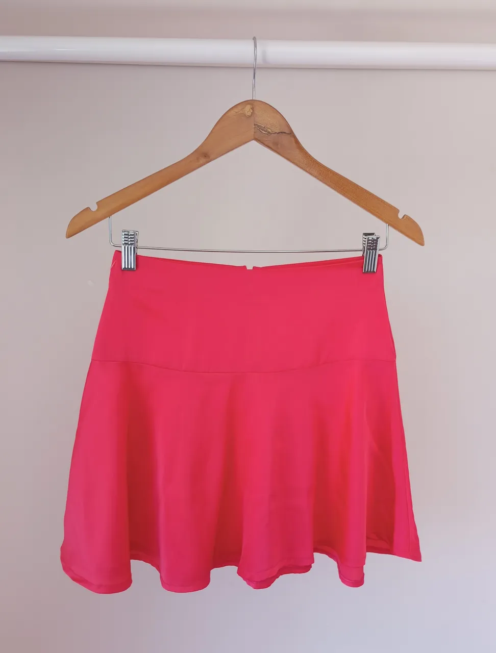 Pollera corta color rosa fuerte, con cierre en la espalda.