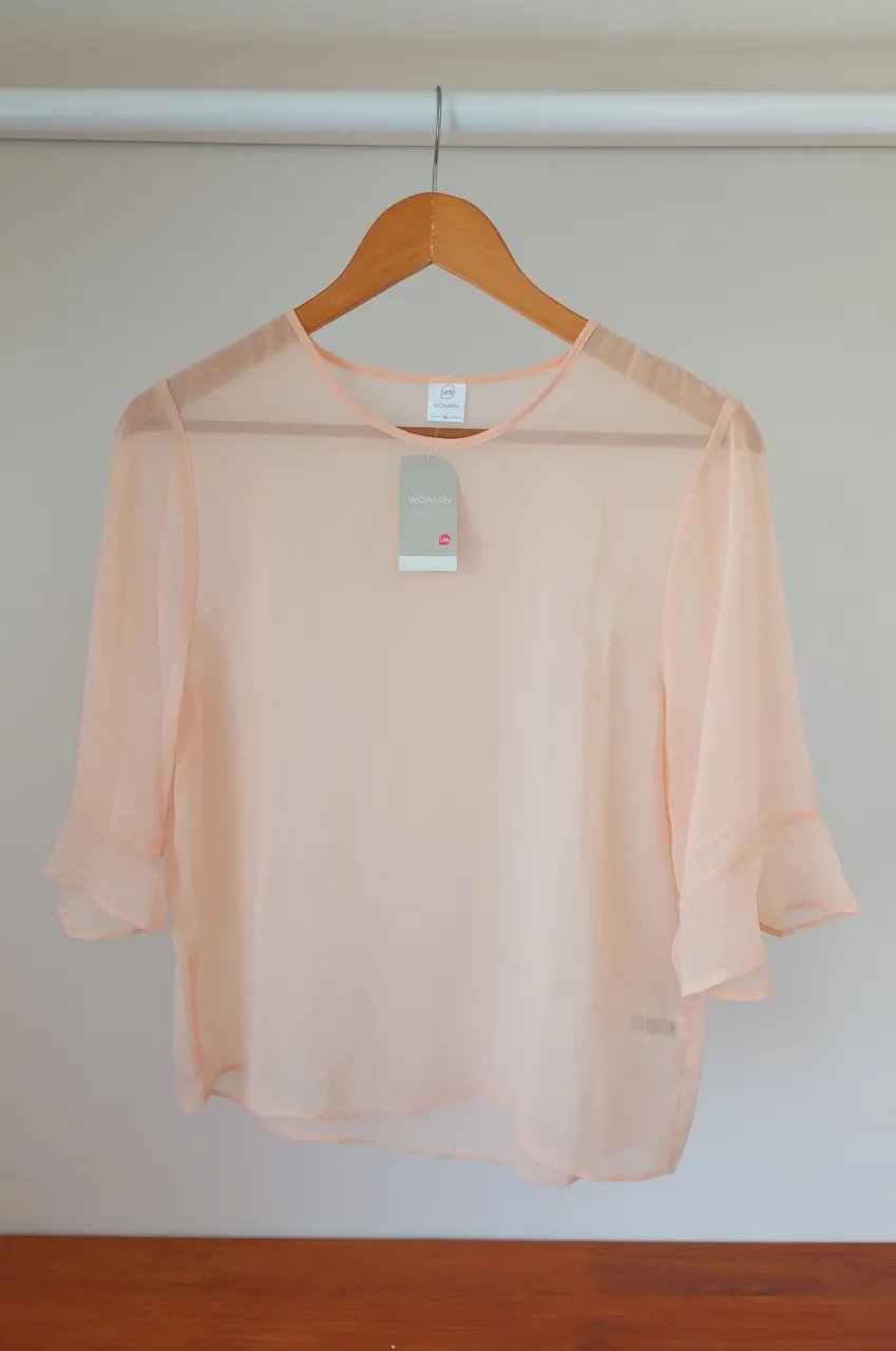 Blusa de seda color durazno, con mangas cortas acampanadas. Ideal para un look elegante y delicado.