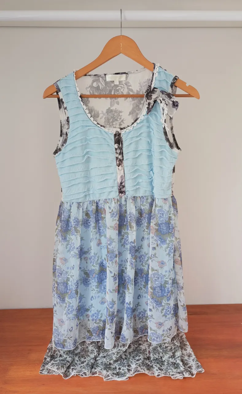 Vestido súper romántico y delicado, ideal para un día de primavera o verano. Posee un estampado floral en tonos celestes y blancos, con detalles de volados y un moño en el hombro que le dan un toque único. Perfecto para un look casual y femenino.