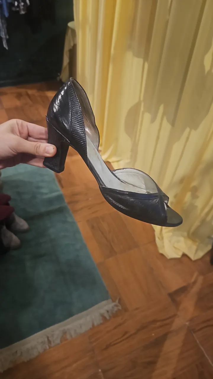 Zapato de taco alto negro, con textura de escamas y punta abierta.