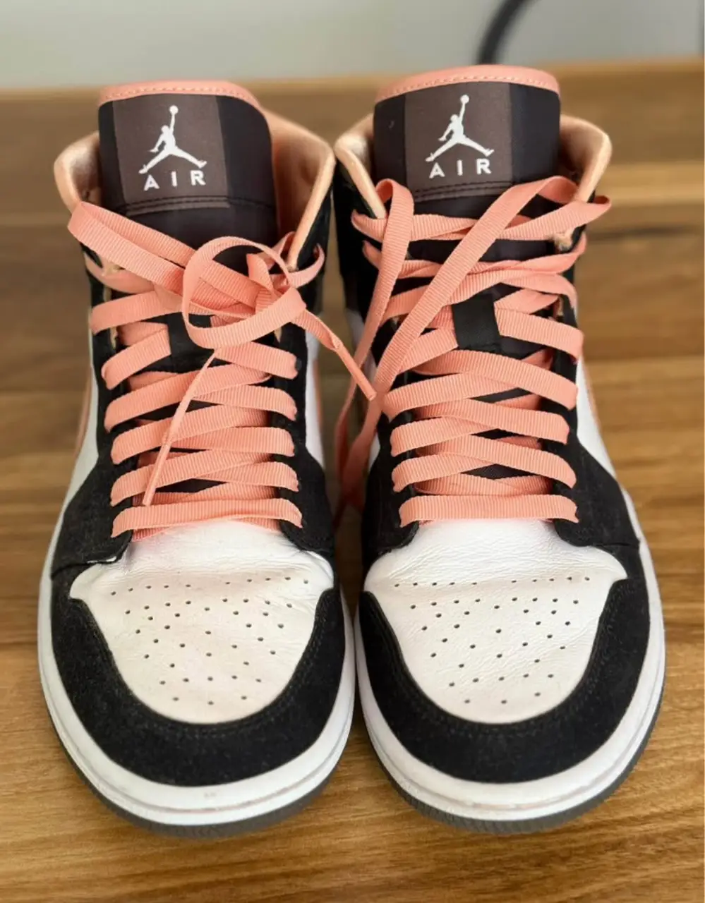 Zapatillas Air Jordan 1 Mid, con detalles en negro, blanco y rosa. Ideales para un look casual y urbano.