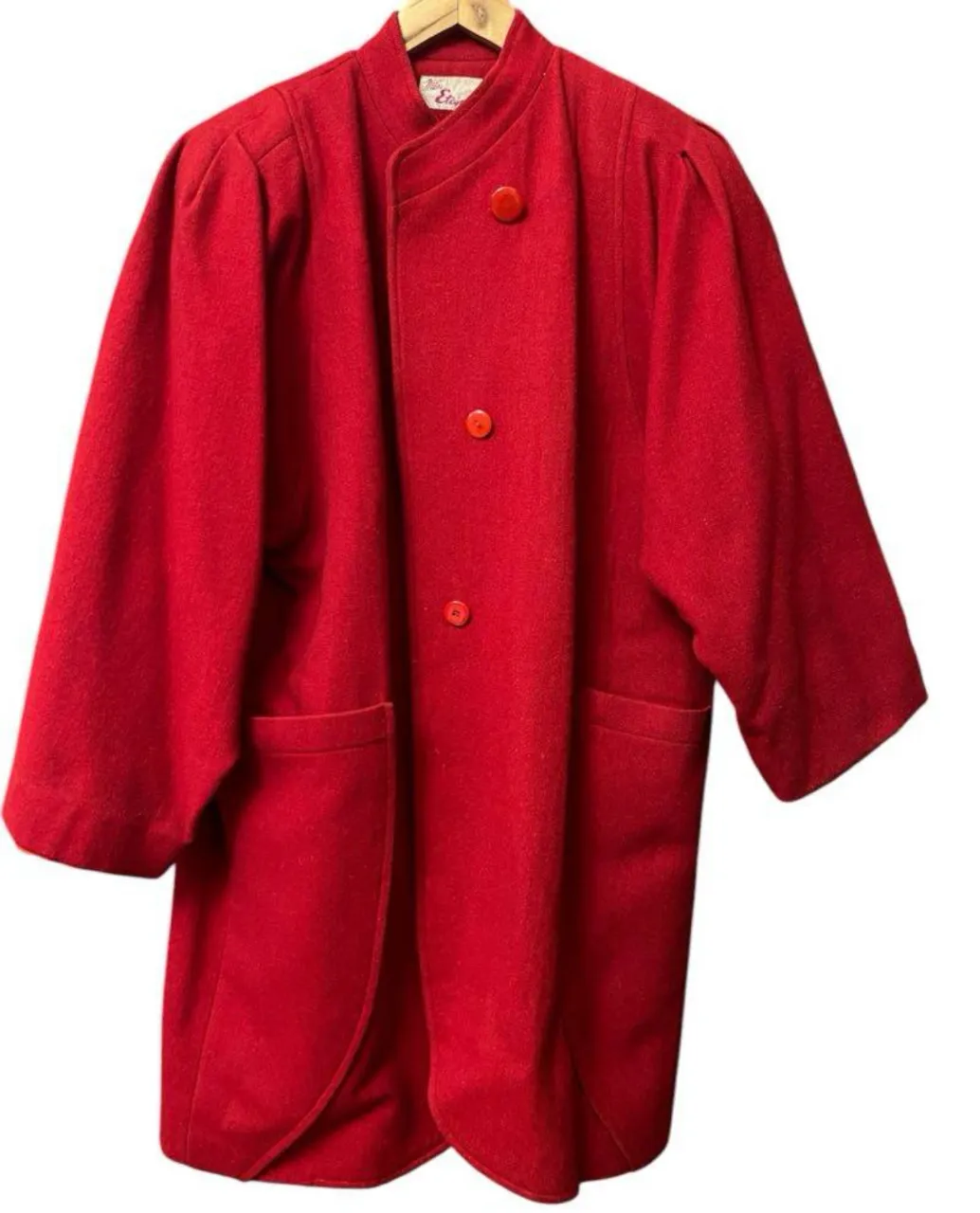 Abrigo rojo de paño con botones y bolsillos. Diseño clásico y elegante, perfecto para un look sofisticado. 100% lana