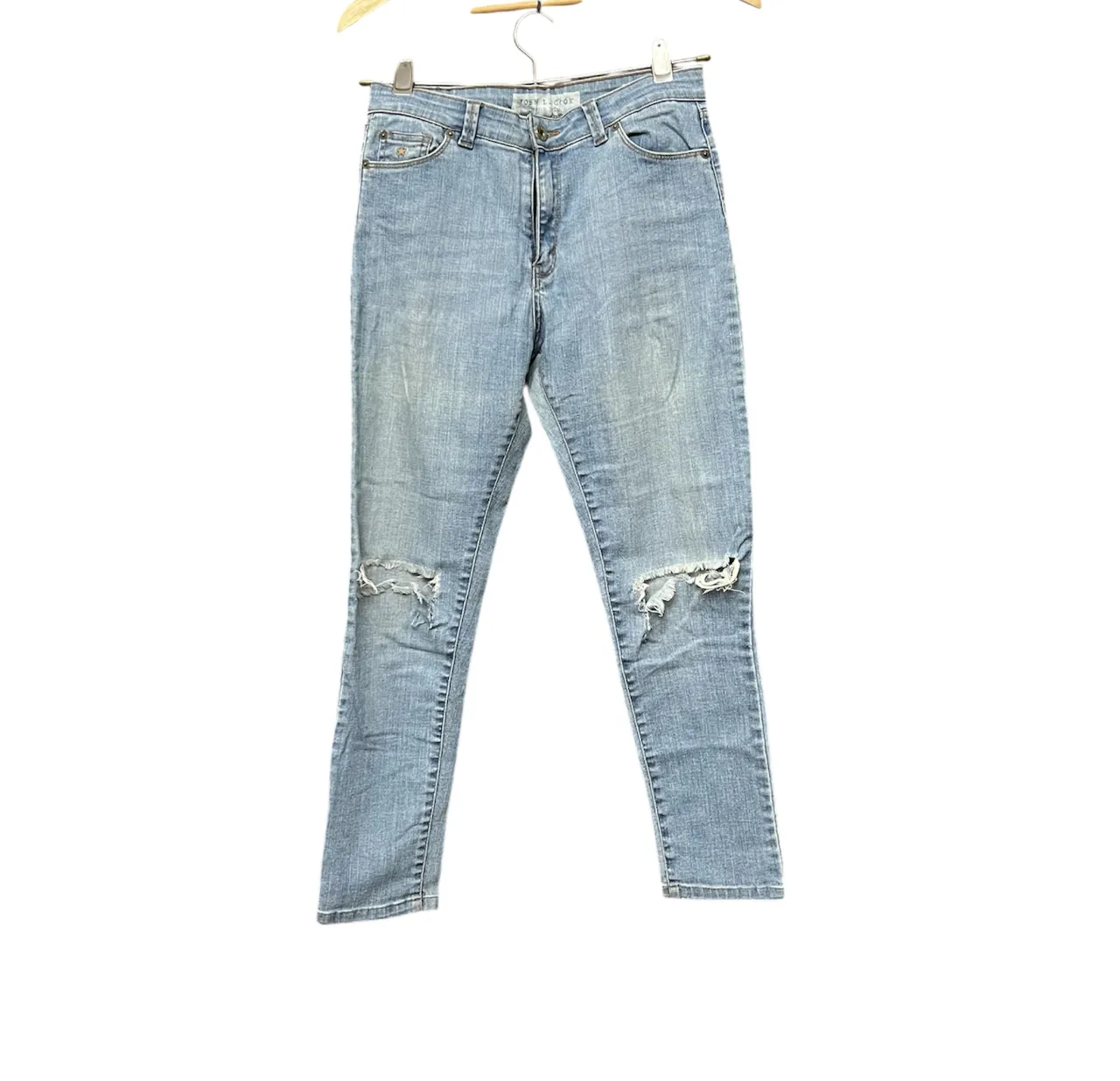 Jeans de tiro alto, color celeste, con roturas en ambas rodillas.