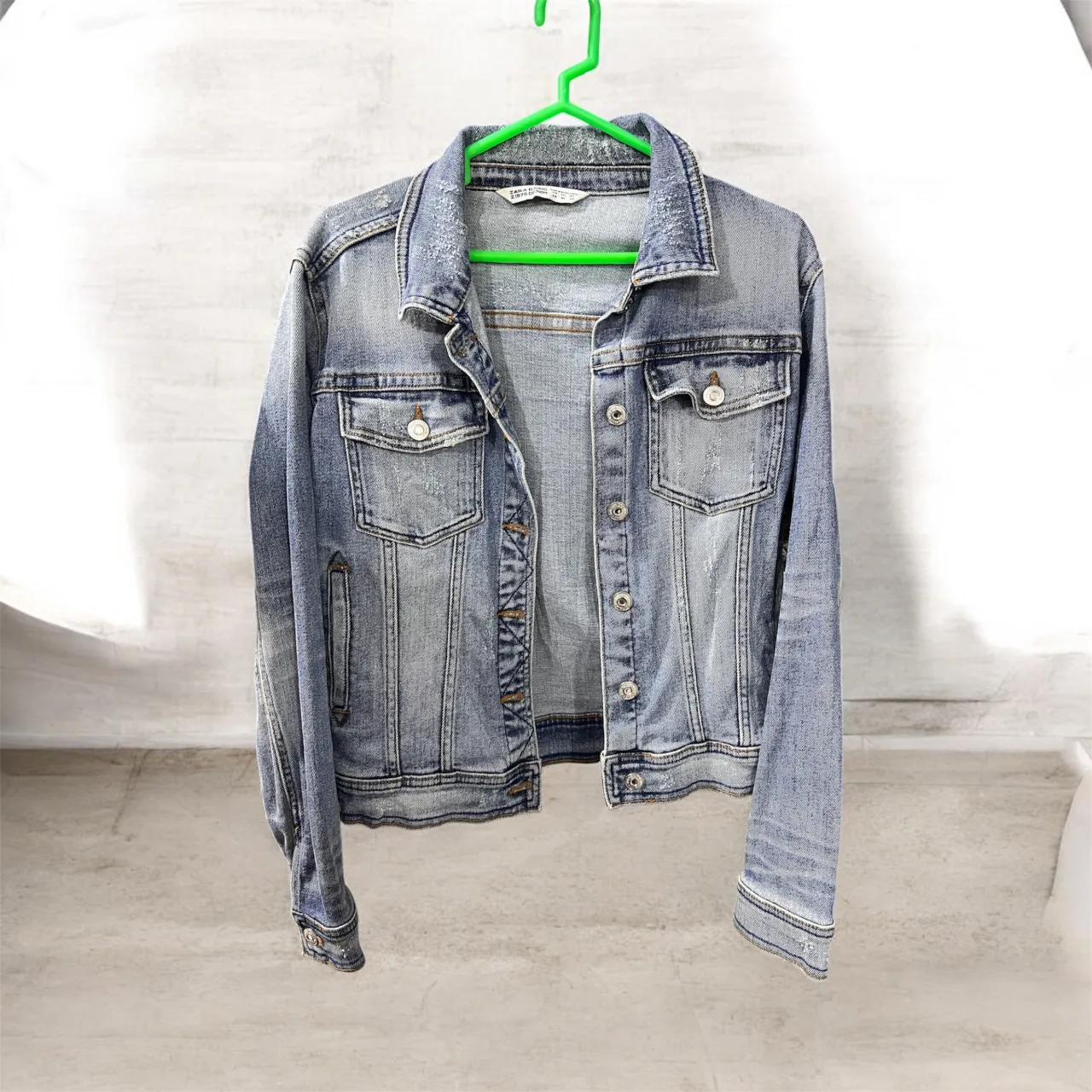 Campera de jean de lavado claro con detalles de roturas y desgaste. Posee bolsillos con solapa en el frente y botones metálicos.