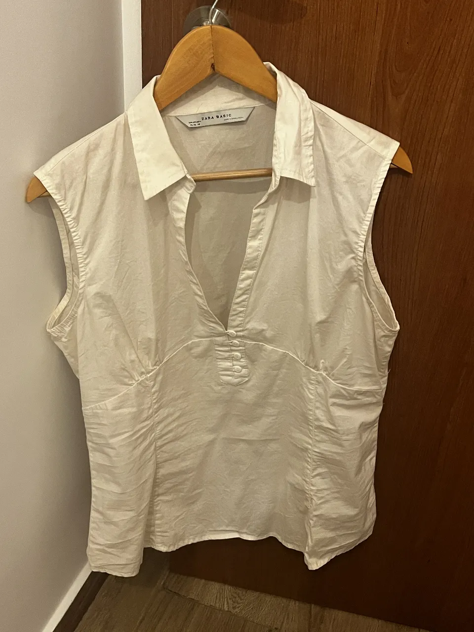 Remera blanca de lino sin mangas, con cuello camisero y escote en V. Posee detalles de botones nacarados en la parte superior y un corte entallado que estiliza la figura. Perfecta para un look casual y fresco.