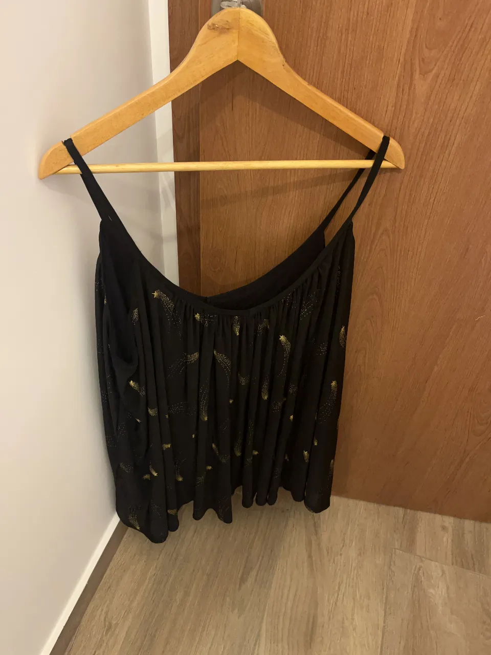 Top negro con estampa de estrellas doradas. Breteles finos y escote amplio. Ideal para un look canchero y moderno.