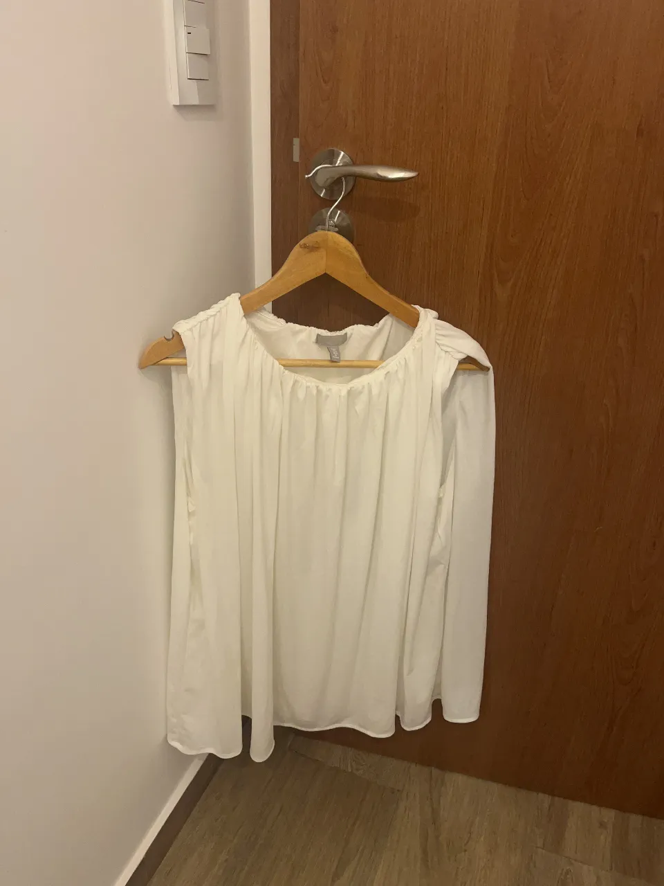 Blusa blanca de mangas largas con detalles plisados en el cuello y los hombros. Un diseño delicado y fresco, ideal para un look casual o elegante.